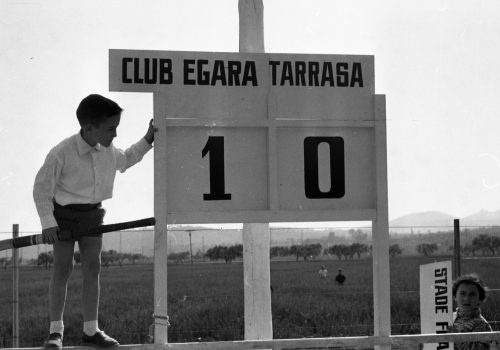<p>Marcador del partit del Club Egara contra el Terrassa, sota l’atenta mirada del jove encarregat.<br />
Fotografia: Joan Biarnés – Procedència: Arxiu Municipal de Terrassa (AMAT) – Reg: 526_014</p>
